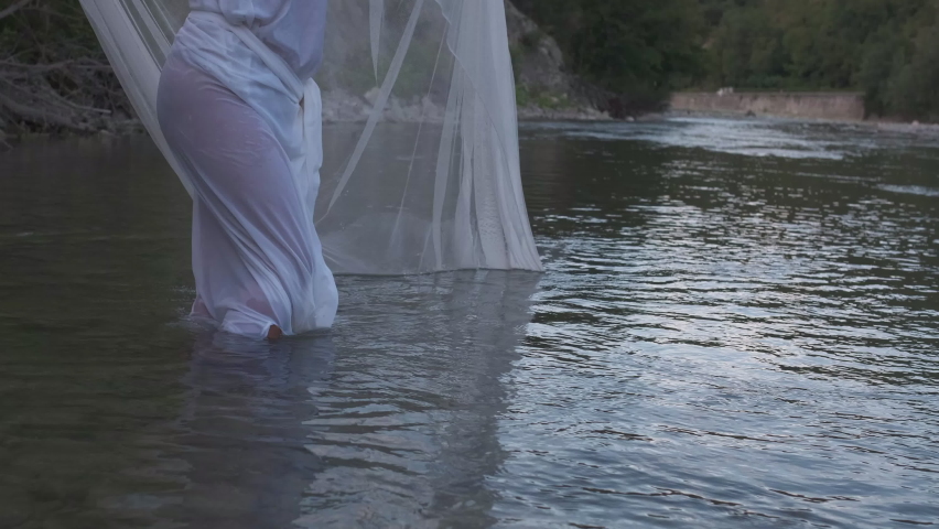 beautiful girl in the river with wet white dress