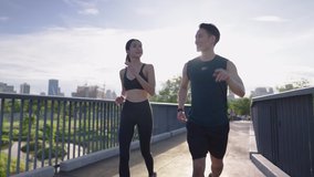 An active asian young couple in sportswear enjoy running jogging outdoors on park walking bridge. Happy athlete people on cheerfully talking while working out. Concept Healthy Motivation and Exercise - Powered by Shutterstock - Get 15% off with code: PIKWIZARD15