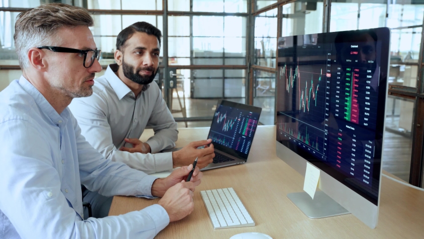Two diverse crypto traders brokers stock exchange market investors discussing trading charts research reports growth using pc computer looking at screen analyzing invest strategy, financial risks. Royalty-Free Stock Footage #1091098453
