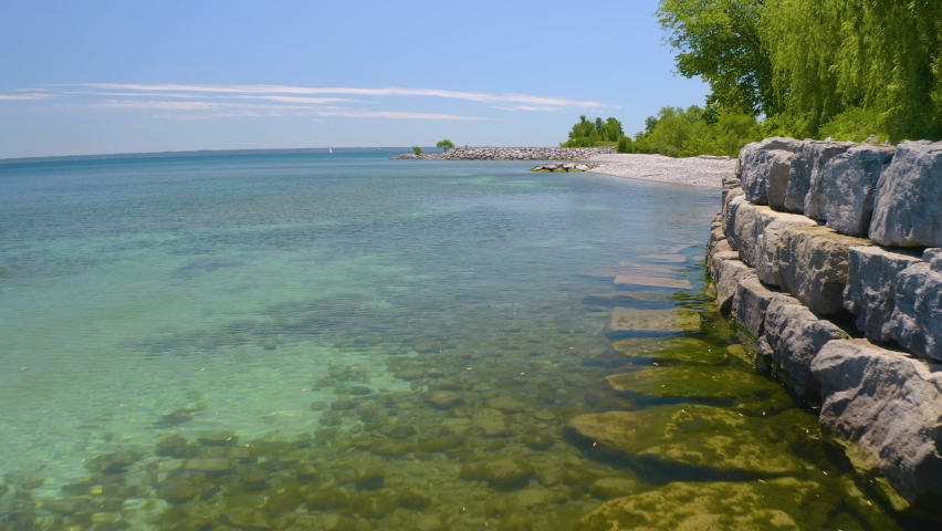 4K Aerial view of Lake Ontario on summer day. Drone rises from water level and heads out over the water.