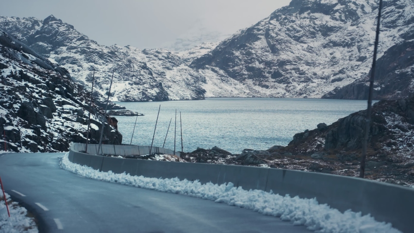 Drive along the Tourist route Ryfylke in late autumn. The light first snow dusted over the mountains and hills. Slow-motion, pan forward.