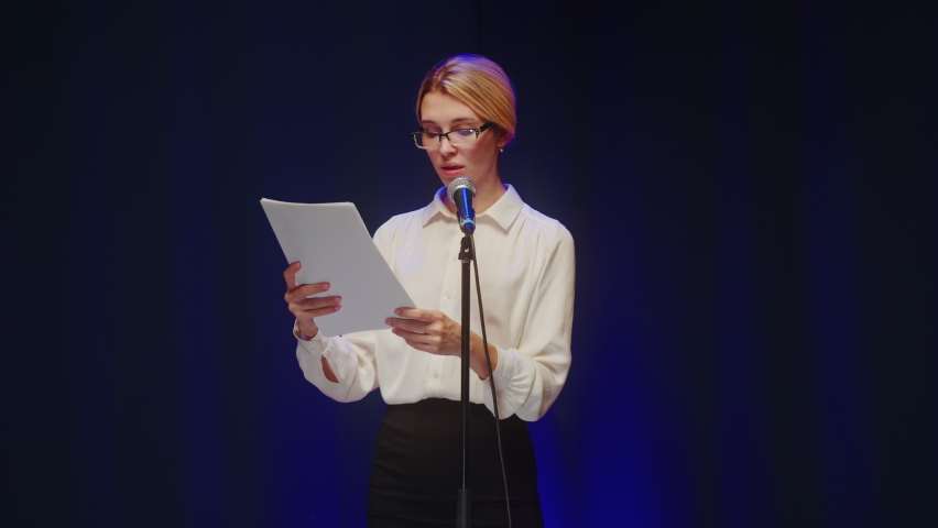 Business training. Young woman giving lecture on stage. Female psychologist speaking with audience using microphone. Mentor coach course, leader manager seminar.