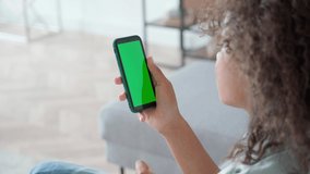 African American girl holding in hands smartphone looking at empty green mockup screen for ads scrolling using mobile apps surfing social media, elearning remotely. Over shoulder view. Closeup. - Powered by Shutterstock - Get 15% off with code: PIKWIZARD15