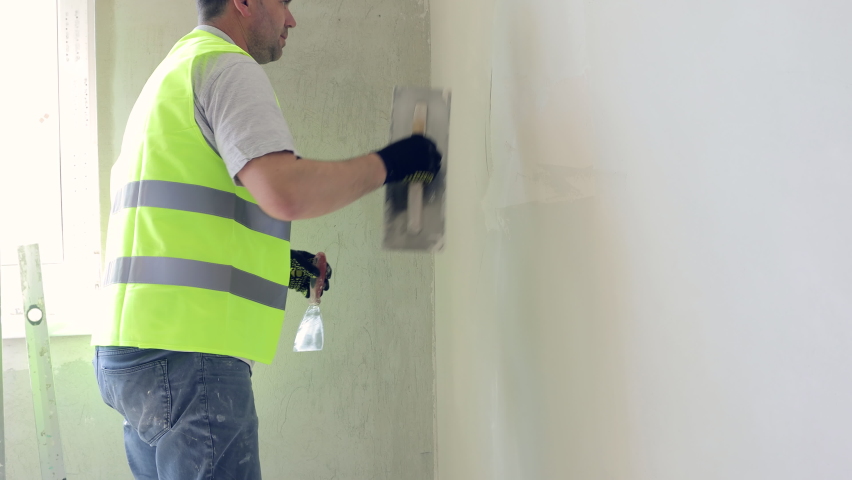 Painting and plastering works on construction sites. The master of apartment renovation levels the walls with starting plaster. Royalty-Free Stock Footage #1091104899