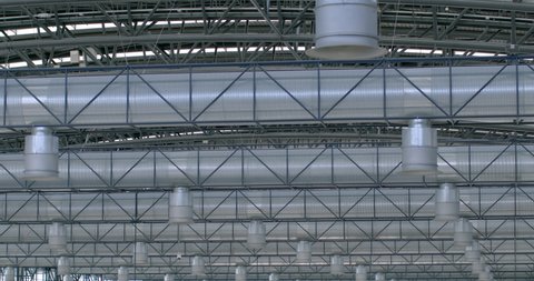 Ventilation systems on ceilings of a metal structure. Pipes and air ducts. Large room ventilation system. Fastening for metal parts. Lightweight construction.