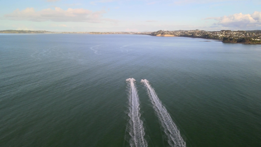 Flying quickly behind 2 jet skis along the coast of Orewa beach in New Zealand at sunset