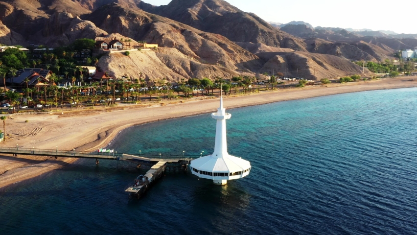 Aerial orbit of the Underwater Observatory Marine Park in Eilat, Israel. The white architecture is complimented by the deep blue water color, beach and rich desert mountain range in the background. Royalty-Free Stock Footage #1091108469