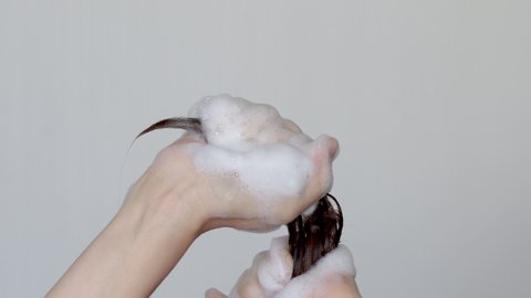 woman is washing hair with shampoo.beauty,hair care concept.girl hand holding hair in ponytail and drags,removing the foam.unrecognizable young woman,isolated