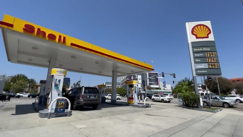 LOS ANGELES, June 8th, 2022: High gas prices. Ultra wide view of a car at a Shell gas station whose sign is displaying prices of just under 8 dollars a gallon.