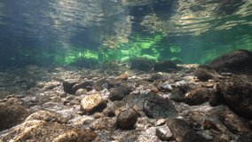 Underwater landscape in a river in shallow water with small rocks and ripples of water surface, Spain, Galicia
