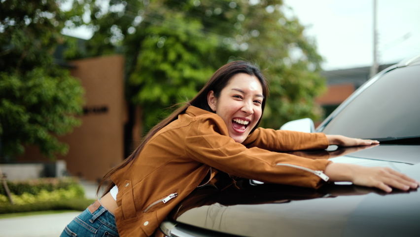 Surprised young asian woman getting the new car. She hugged his car and was very happy. Buy or rent car concept.