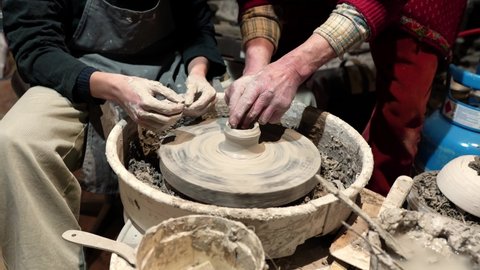 Pottery training in potter's workshop. hands of master potter and apprentice's apprentice form clay into mold on potter's wheel