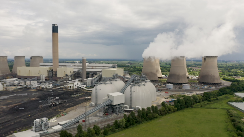 4K aerial drone footage of a large coal fired power station with biofuel biomass being delivered by freight train into large storage tanks to reduce air pollution emissions Royalty-Free Stock Footage #1091120409