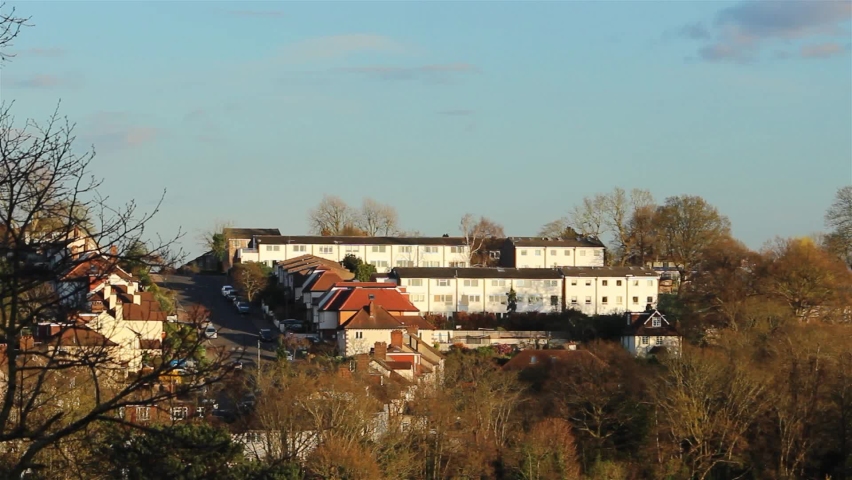 Car Driving Uphill On Quiet Road. Houses On Hilltop.