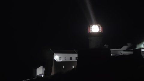 Cape St. Vincent Lighthouse radiating light with its rotating lens at night, Portugal. Powerful lamp in the darkness. Maritime navigation