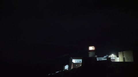 Night speed-up shot of Cape St. Vincent Lighthouse, Portugal. Beam of light coming from rotating lens and striking through the total darkness. Maritime navigation