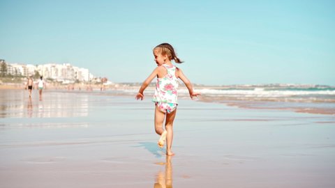 Child running ocean beach summer day Little girl caucasian have fun run on sand seashore Adorable female 5 years old enjoy playing on beach runs away from camera Handheld. High quality FullHD footage