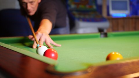 A man misses a shot while playing pool on a pool table in a bar