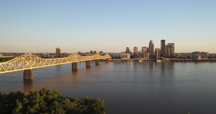 Louisville, Kentucky skyline with bridge and trees with drone video moving down.