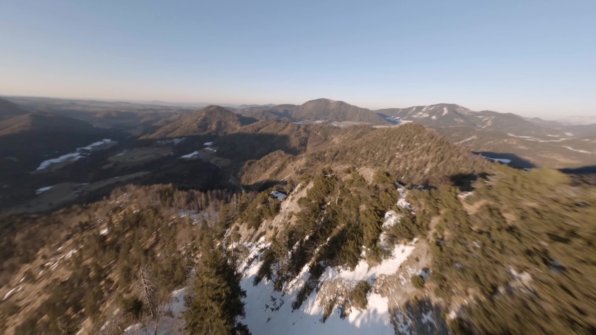 fpv drone diving down an austrian mountain at spring in the evening sun