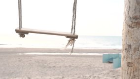 Wooden swings on sandy white beach at sunset, close up. Peaceful calm beach 4K summer holiday sea or ocean background.