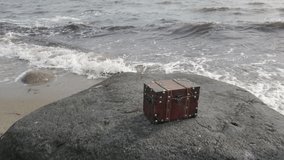 Treasure chest on rock at Baltic Sea beach with rushing waves, 4k video footage