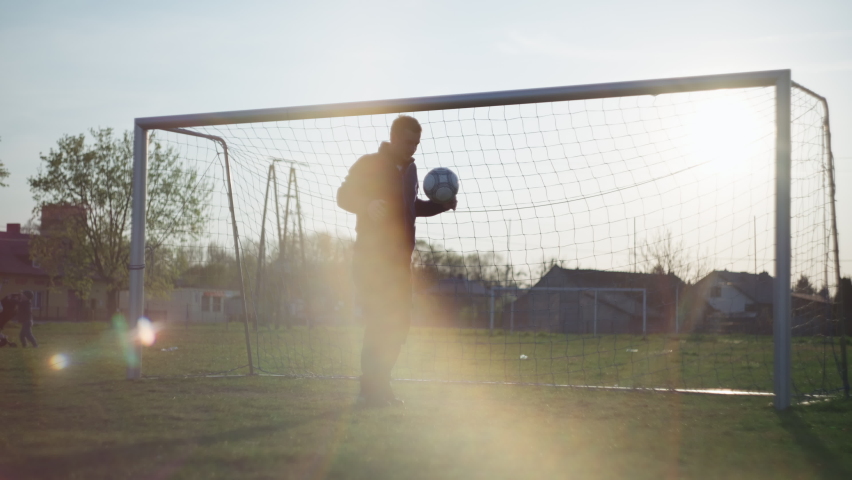 The guy stuffs the ball at the football goal. Amateur soccer workout with ball at sunset slow motion video. Mass sports. | Shutterstock HD Video #1091138575
