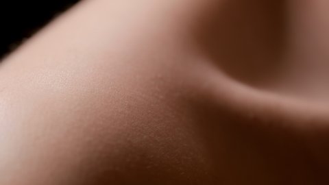 Macro shot of two water drops fall down on bare shoulder of white-skinned female model on black background | Skin texture shot for skincare serum commercial