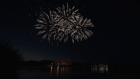 Awesome Real Firework on Deep Black Background Sky on Fireworks festival from river bank over night city lights in summer on 4th of July, Independence day in USA 2022. High quality 4k raw video