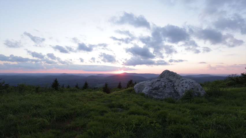 The sun sets over the Allegheny Mountains in West Virginia on a summer evening, seen from a grassy meadow on Spruce Knob, the highest point of the state, within the Monongahela National Forest.  