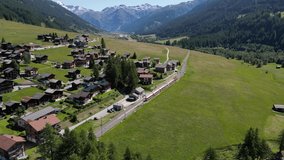 Aerial footage of train leaving station in mountain Swiss village. European transportation system. Railway of Switherland
