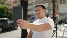 Young chinese man smiling confident having video call at street
