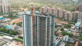 aerial orbiting shot of under construction skyscraper with crane and workers with parallax effect with the smaller houses and buildings in the background shot at dusk in the city of gurgaon delhi - Powered by Shutterstock - Get 15% off with code: PIKWIZARD15