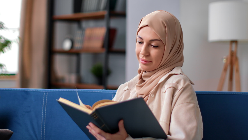 Muslim woman in hijab headscarf reading vintage religious book enjoy interesting literature hobby at home couch. Beautiful Arabic female relaxing with educational paper textbook leisure activity - Powered by Shutterstock - Get 15% off with code: PIKWIZARD15