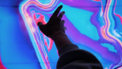 NIZHNY NOVGOROD, RUSSIA - JANUARY 8, 2022: Augmented reality event - woman moves her arm against colorful large futuristic wall display at immersive exhibition - close up, digital art installation Video stock editoriale