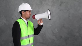 a disgruntled male Arab builder on a gray background in a yellow vest and a white helmet yells loudly into the loudspeaker. Megaphone in the hands of a worker. - Powered by Shutterstock - Get 15% off with code: PIKWIZARD15