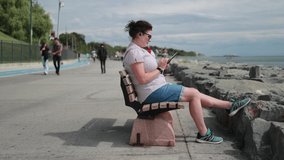 A young brunette woman uses a smartphone, talks, takes pictures and shoots video