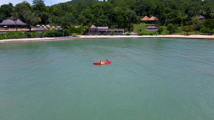 Couple in a kayak in the ocean of Phuket Thailand, men and woman in a kayak at a tropical island with palm trees and mangrove forest. 