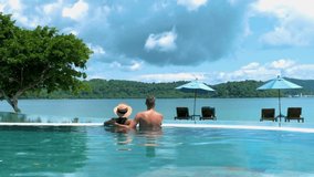 couple European man and an Asian woman in an infinity pool in Thailand looking out over the ocean, a luxury vacation in Thailand.  - Powered by Shutterstock - Get 15% off with code: PIKWIZARD15