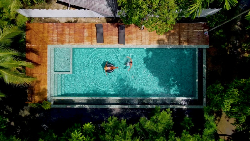 couple men and woman in swimming pool in the jungle of Krabi Thailand, aerial view with drone above swimming pool in jungle of Thailand.  Royalty-Free Stock Footage #1091172691