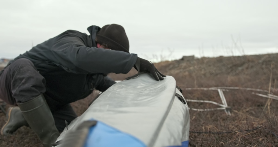 man in glasses assembles kayak putting reinforcing elements