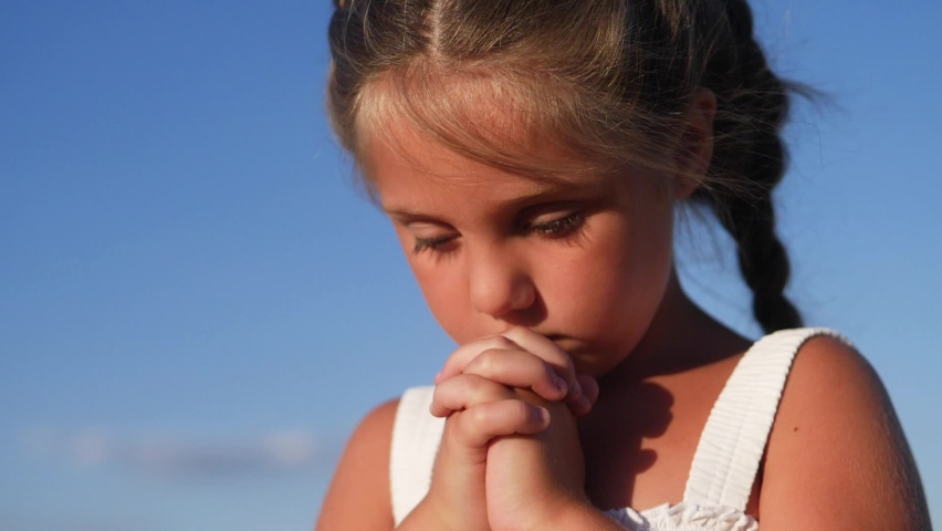 girl kid pray against a blue sky. child close-up concept faith religion and happy family. kid daughter jew crossed arms praying to god. kid pray worship and catholic gratitude and a happy childhood Royalty-Free Stock Footage #1091180587