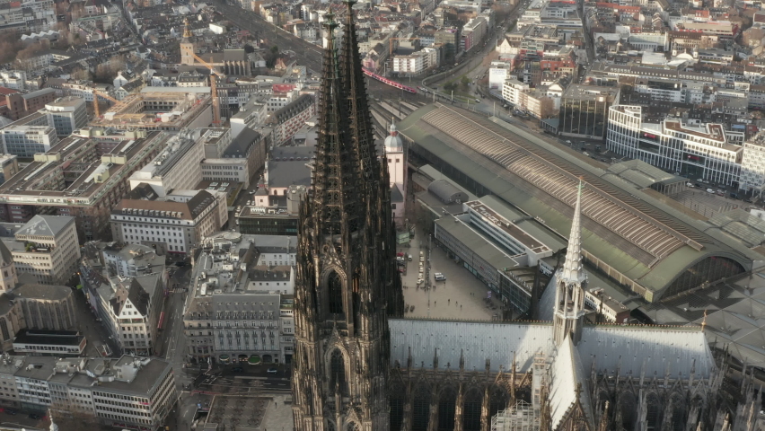 Aerial descending shot of tall tower of gothic Cologne Cathedral. Tilt up reveal panoramic view of large city. Cologne, Germany