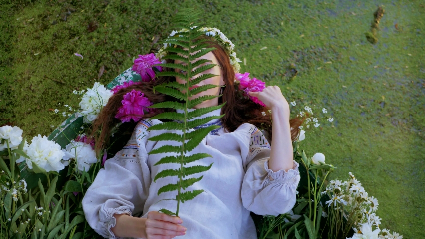 Beautiful girl lying in a boat. Young woman lying in flowers on the river.