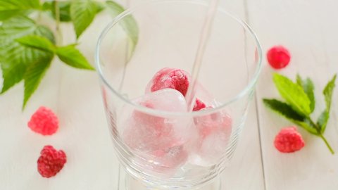 Raspberry summer cocktail.Mineral water is poured into a glass. High quality 4k footage