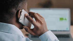 Backside unknown african american man young businessman web designer look at laptop screen surf internet website scroll page interface in social network talk mobile phone wireless call communication - Powered by Shutterstock - Get 15% off with code: PIKWIZARD15