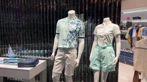 Male and female mannequins without heads stand in the window of a clothing store dressed in shorts and t-shirts. The inscription on the T-shirt: Save the nature!