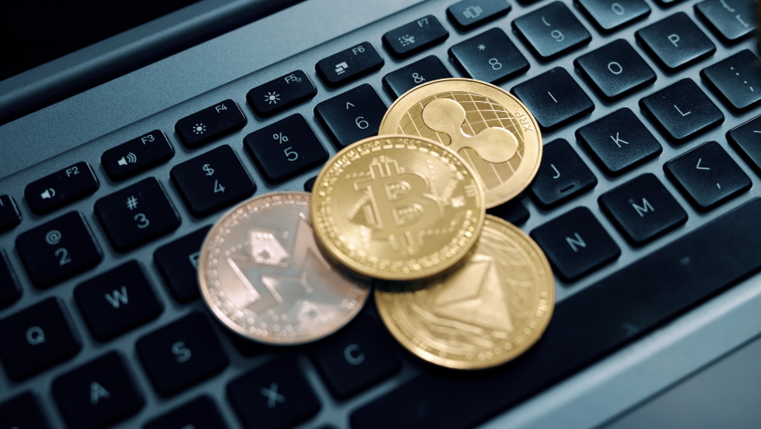 Bitcoin ethereum monero and ripple on the laptop keyboard with magnifier. Investing in virtual assets. Cryptocurrency and altcoins concept