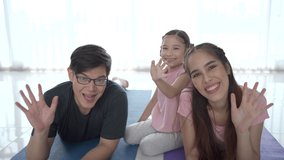 4K footage showing a cheerful happy Asian family with father mother and daughter making a home exercise together in the living room and making a video live streaming on social network.