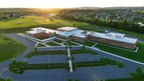 High aerial orbit around large new elementary school in America. Brand new educational building during spring sunset. Athletic fields in background. - Powered by Shutterstock - Get 15% off with code: PIKWIZARD15